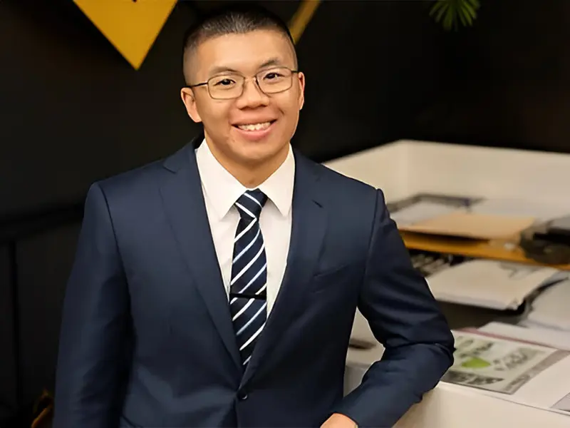 A man in a suit and tie standing next to papers.