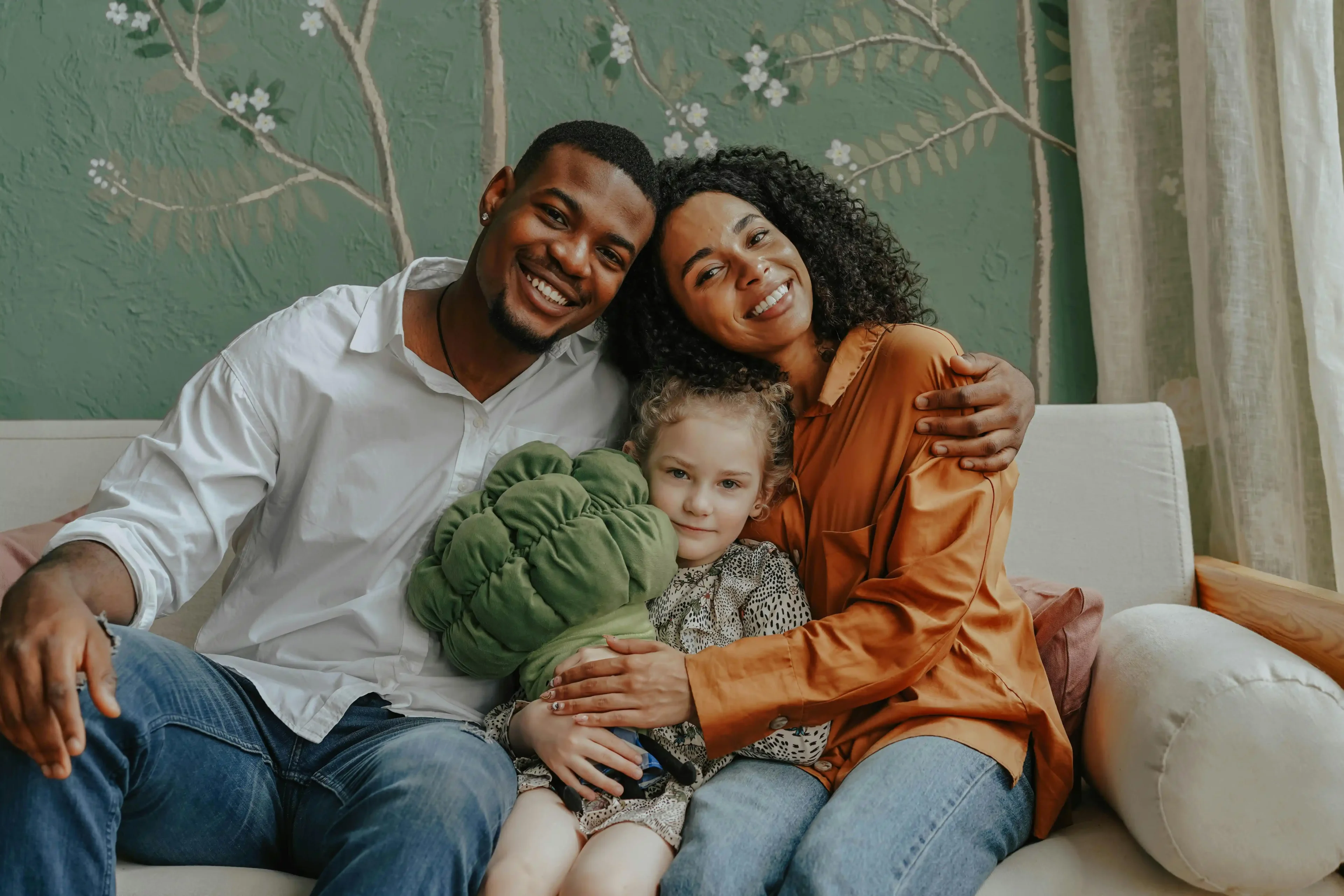 A family sitting on the couch with a stuffed animal.