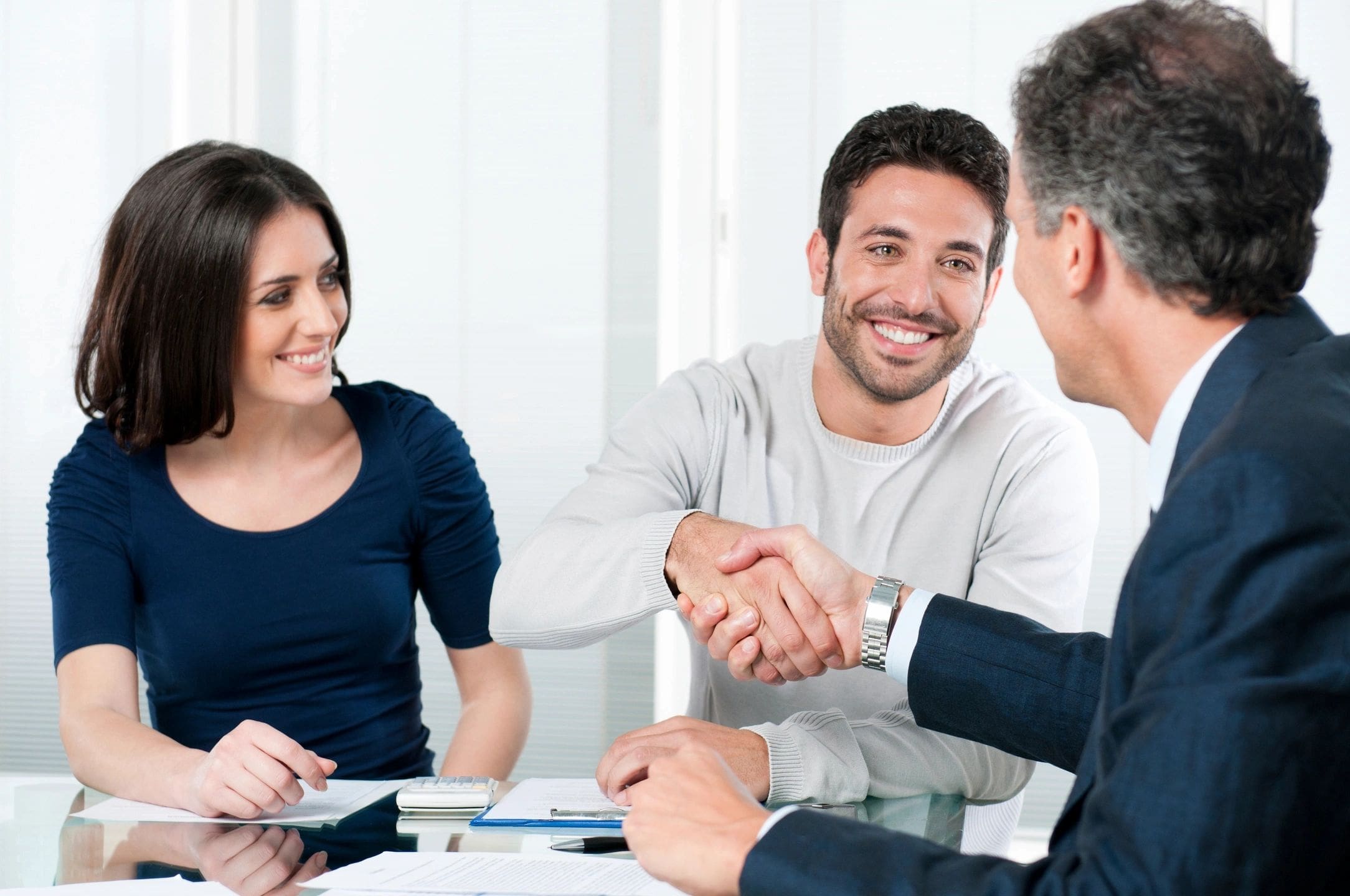 A man and woman shaking hands over a table.